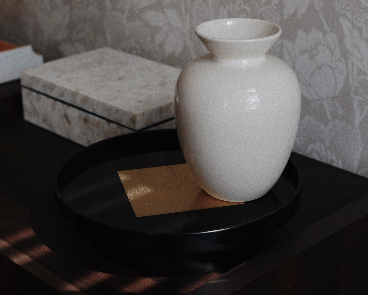 Vinidec black round lacquered tray with central gold leaf foil accent, styled with a ceramic vase in an elegant London home setting