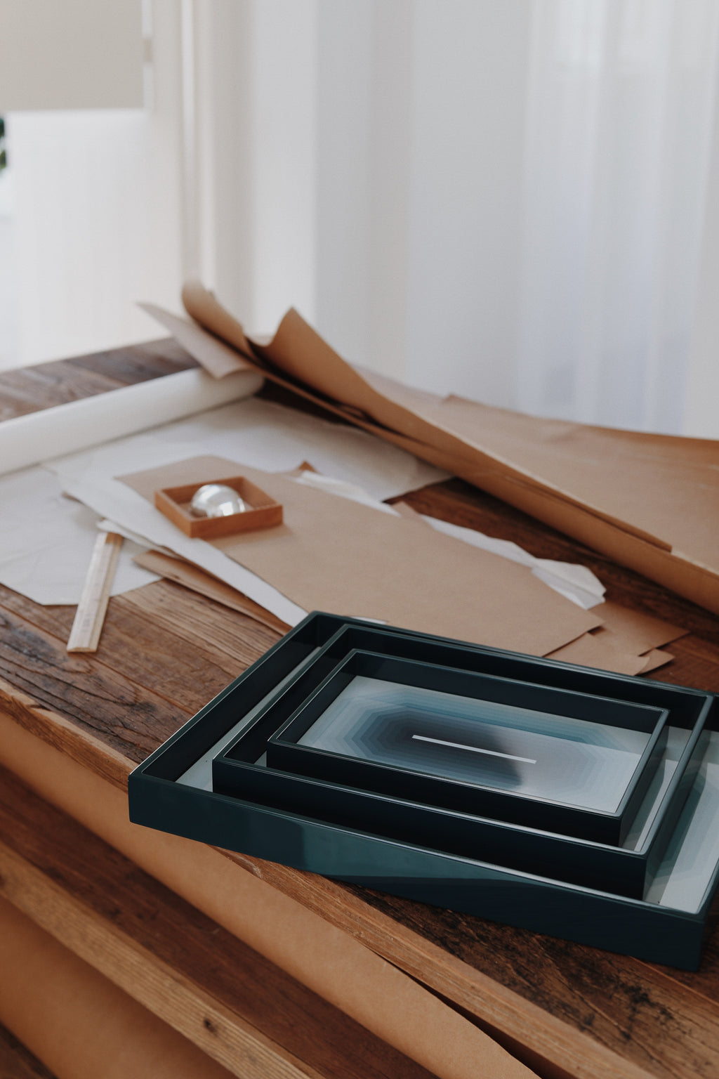 Lacquered trays on a wooden surface with cardboard and other materials in the background