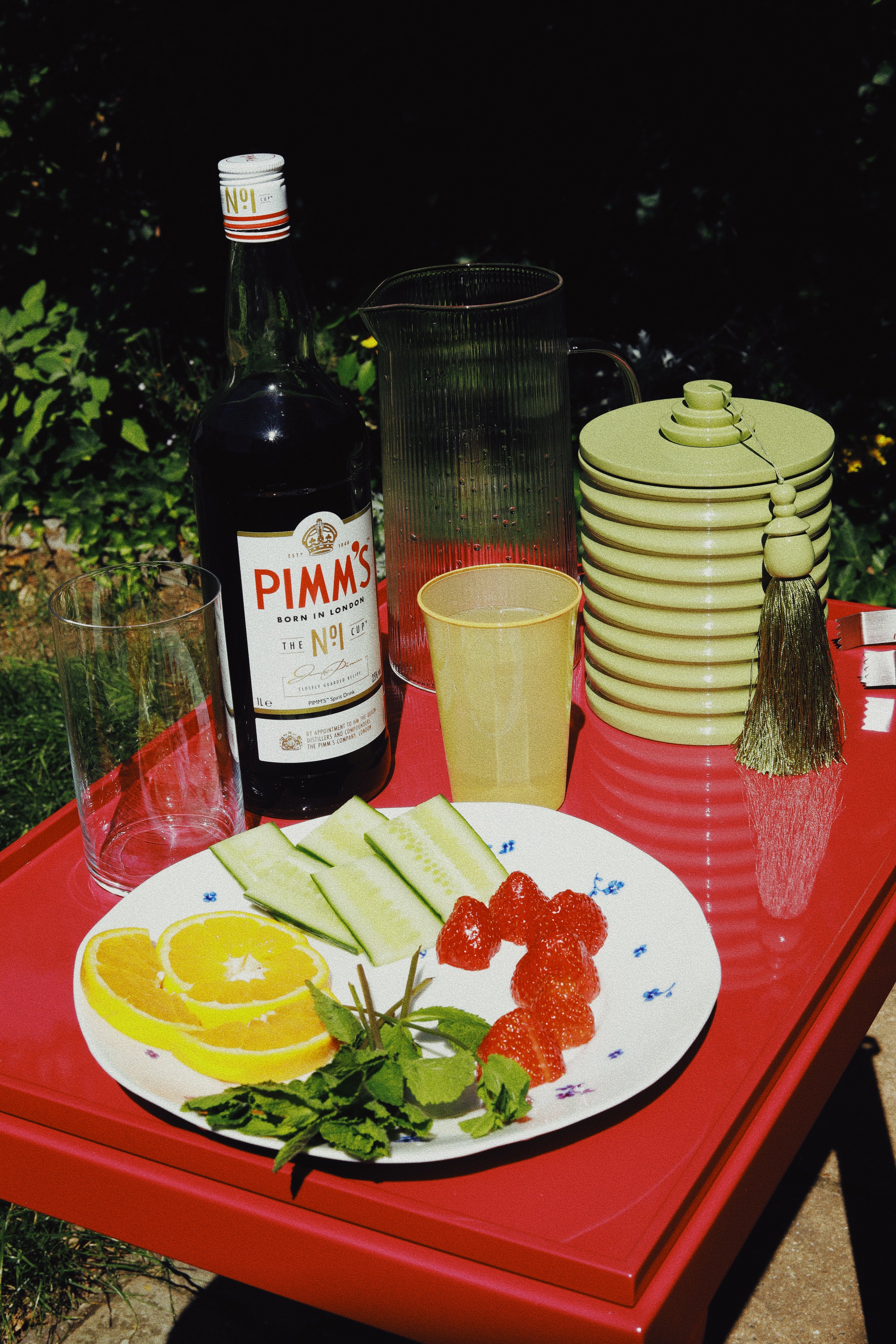 Vinidec Lantern Ice Bucket in pistachio green with silk tassel, styled on a bright pink lacquered tray with Pimm's and summer cocktail ingredients