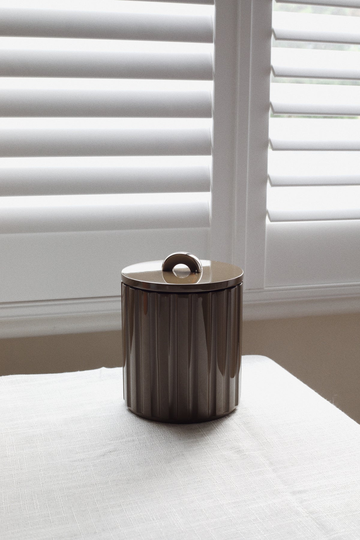 Deep espresso fluted lacquer ice bucket styled on linen for warm autumn bar cart and tablescape design.