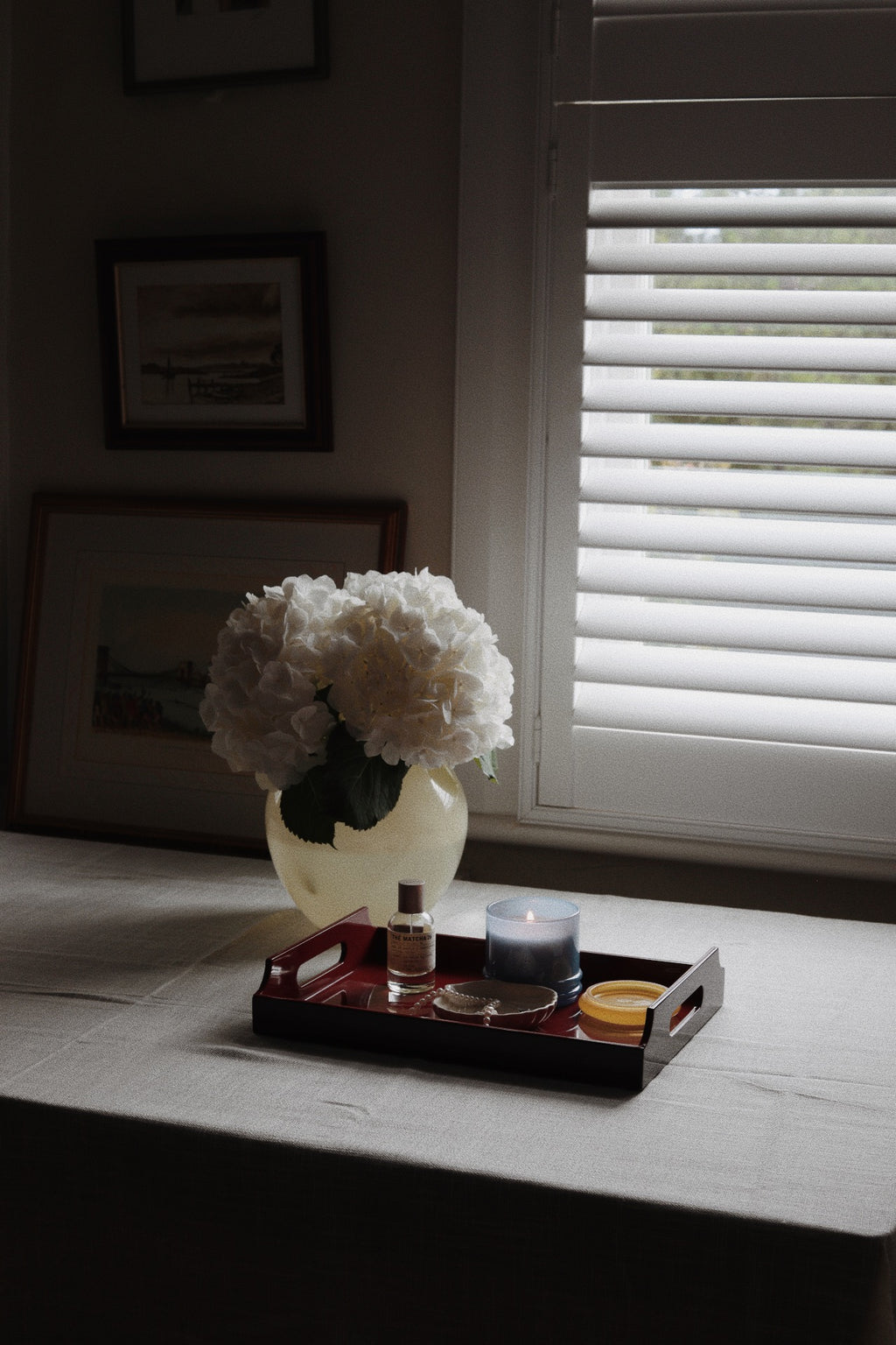 Vinidec small dual-tone lacquered tray in cherry red and sand styled on table with candle perfume and white hydrangeas