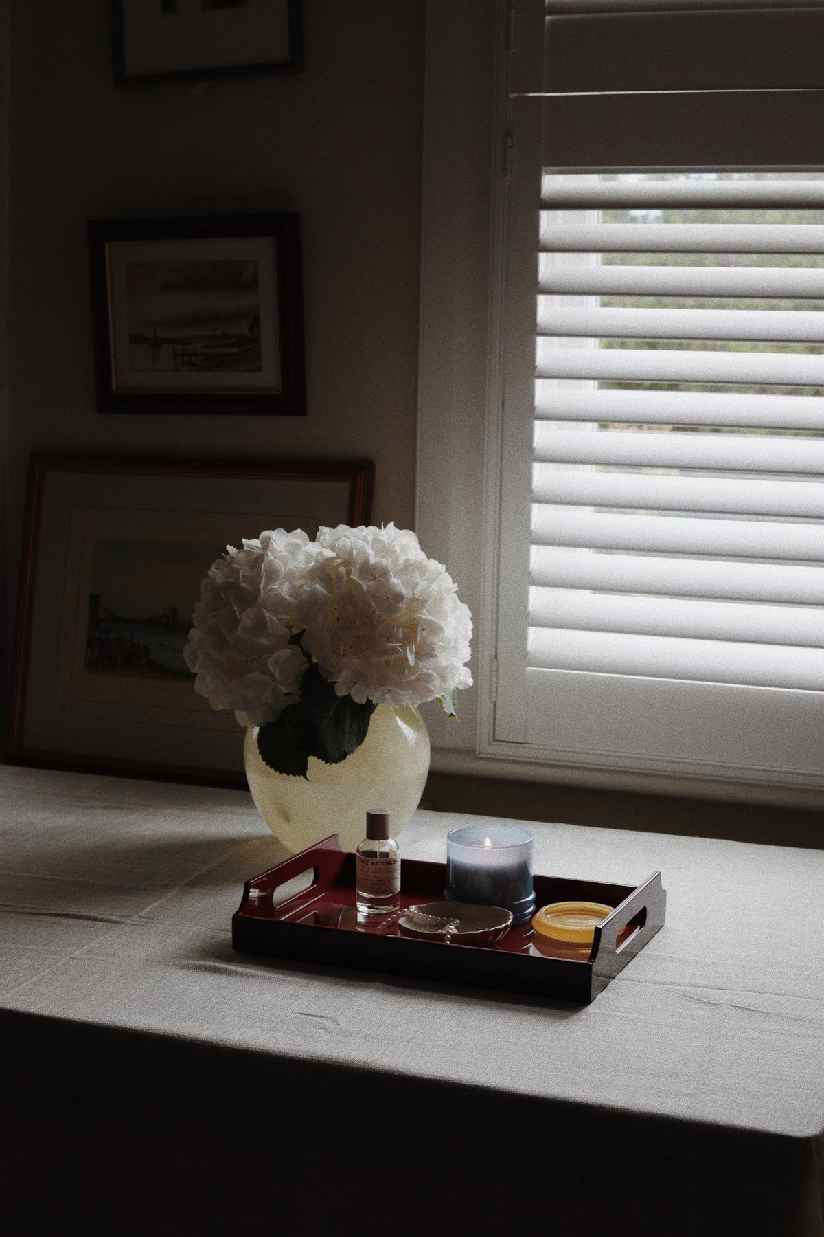 Vinidec small dual-tone lacquered tray in cherry red and sand styled on table with candle perfume and white hydrangeas