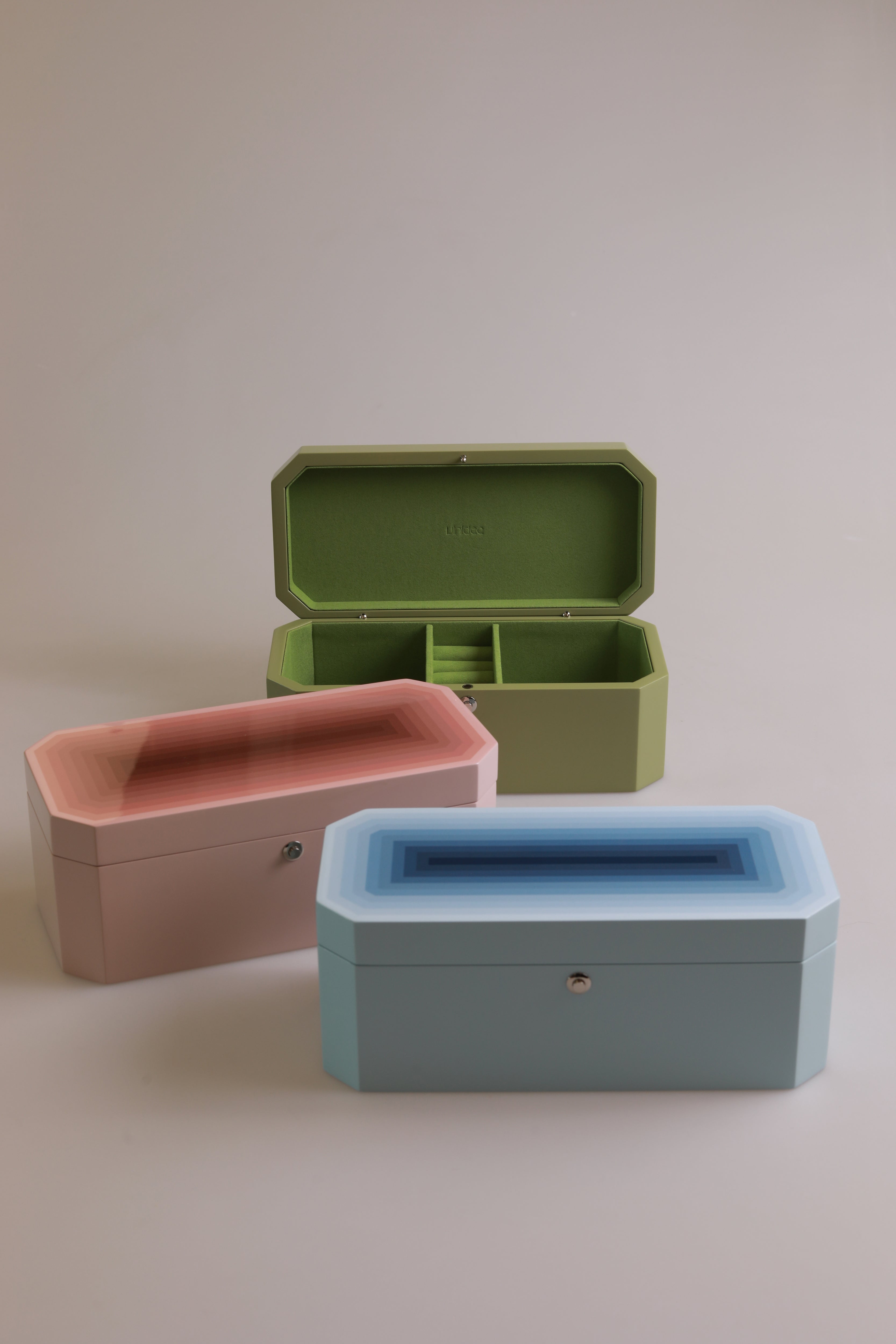 Vinidec Chiaroscuro octagonal jewellery and watch boxes in peach, baby blue, and open pistachio green lacquer showing green velvet interior compartments