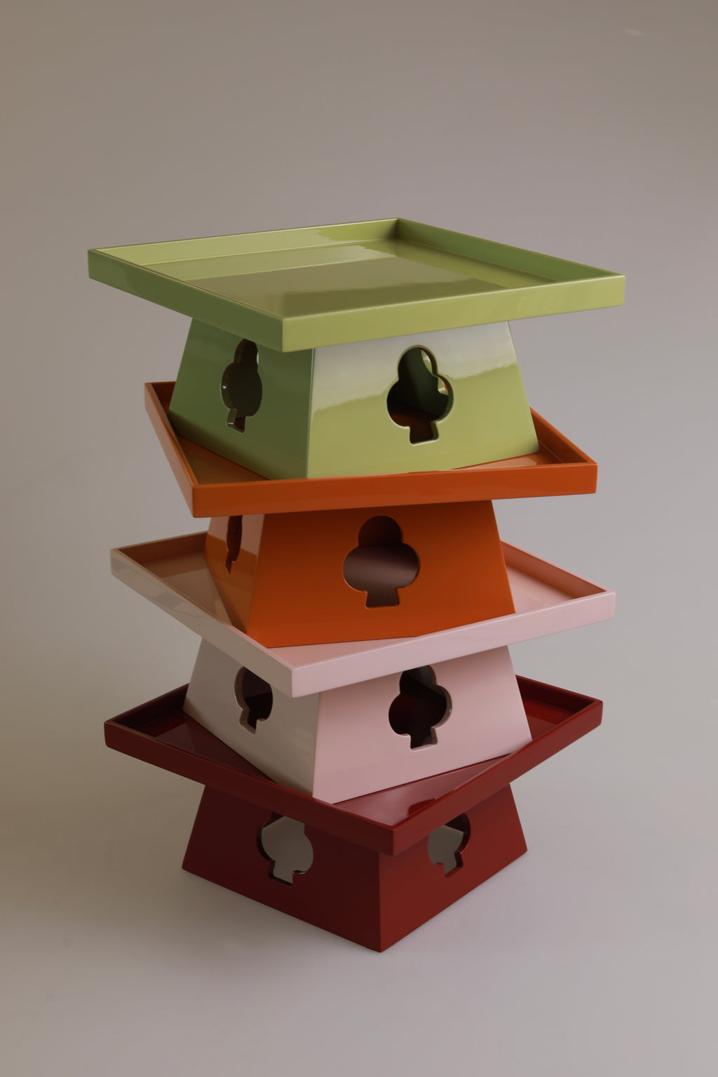 Vinidec elevated trays stacked in pistachio green, orange, dusty pink, and rich red lacquer showing suit cutout bases