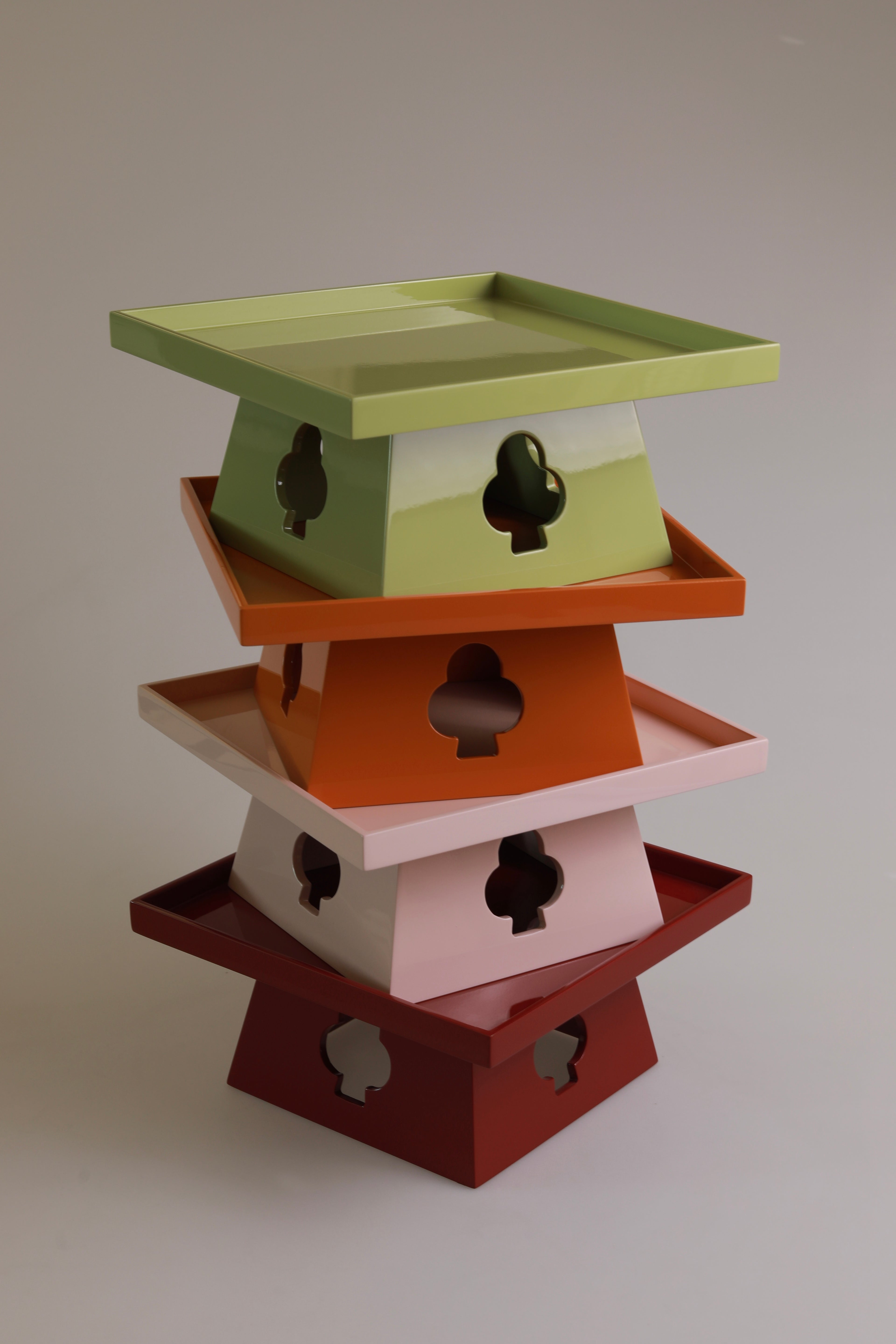 Vinidec elevated trays stacked in pistachio green, orange, dusty pink, and rich red lacquer showing suit cutout bases