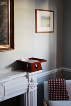 Vinidec elevated tray in rich red gloss finish with playing card cutouts, styled on a white fireplace mantel in an elegant London interior