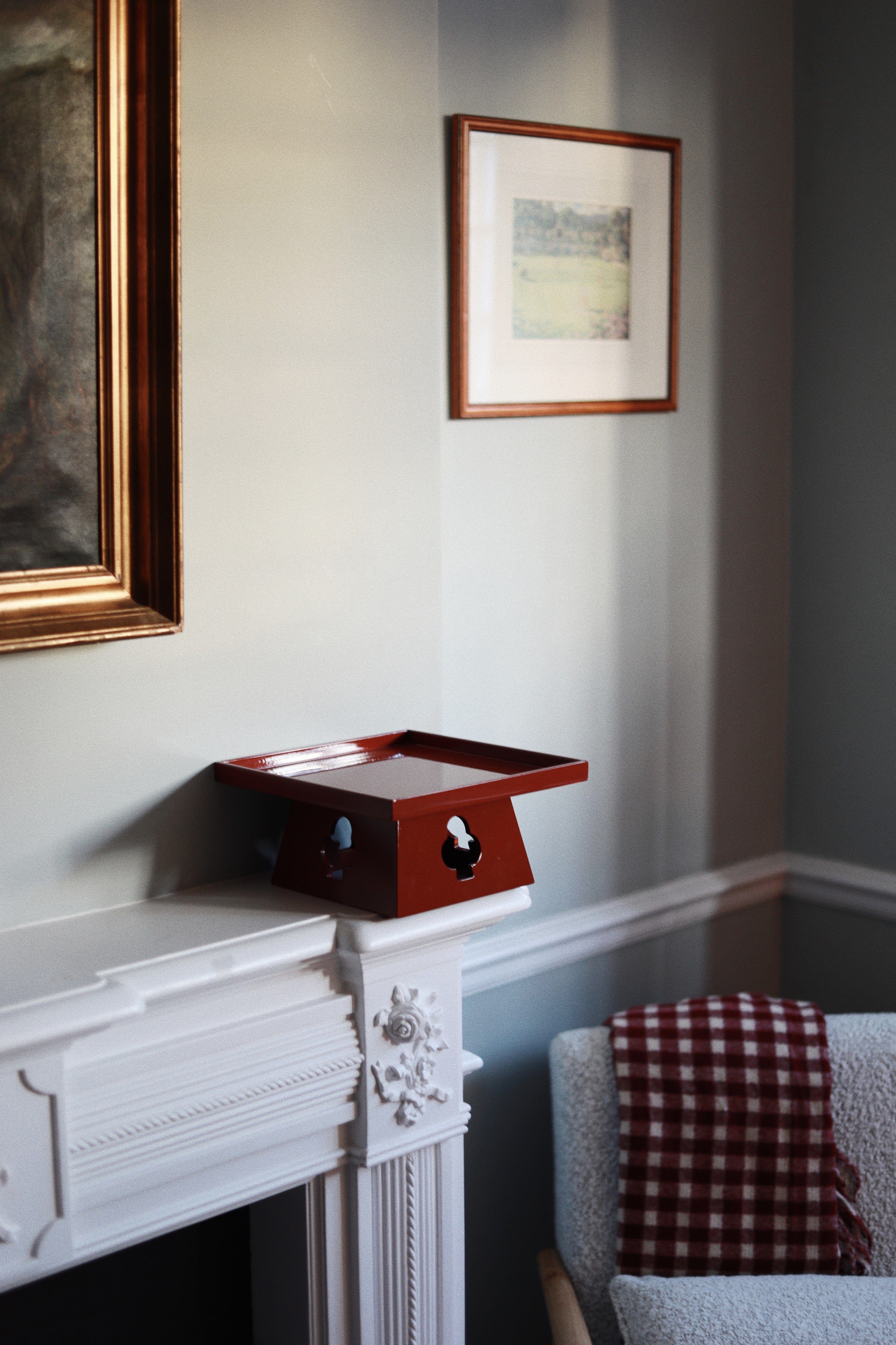 Vinidec elevated tray in rich red gloss finish with playing card cutouts, styled on a white fireplace mantel in an elegant London interior