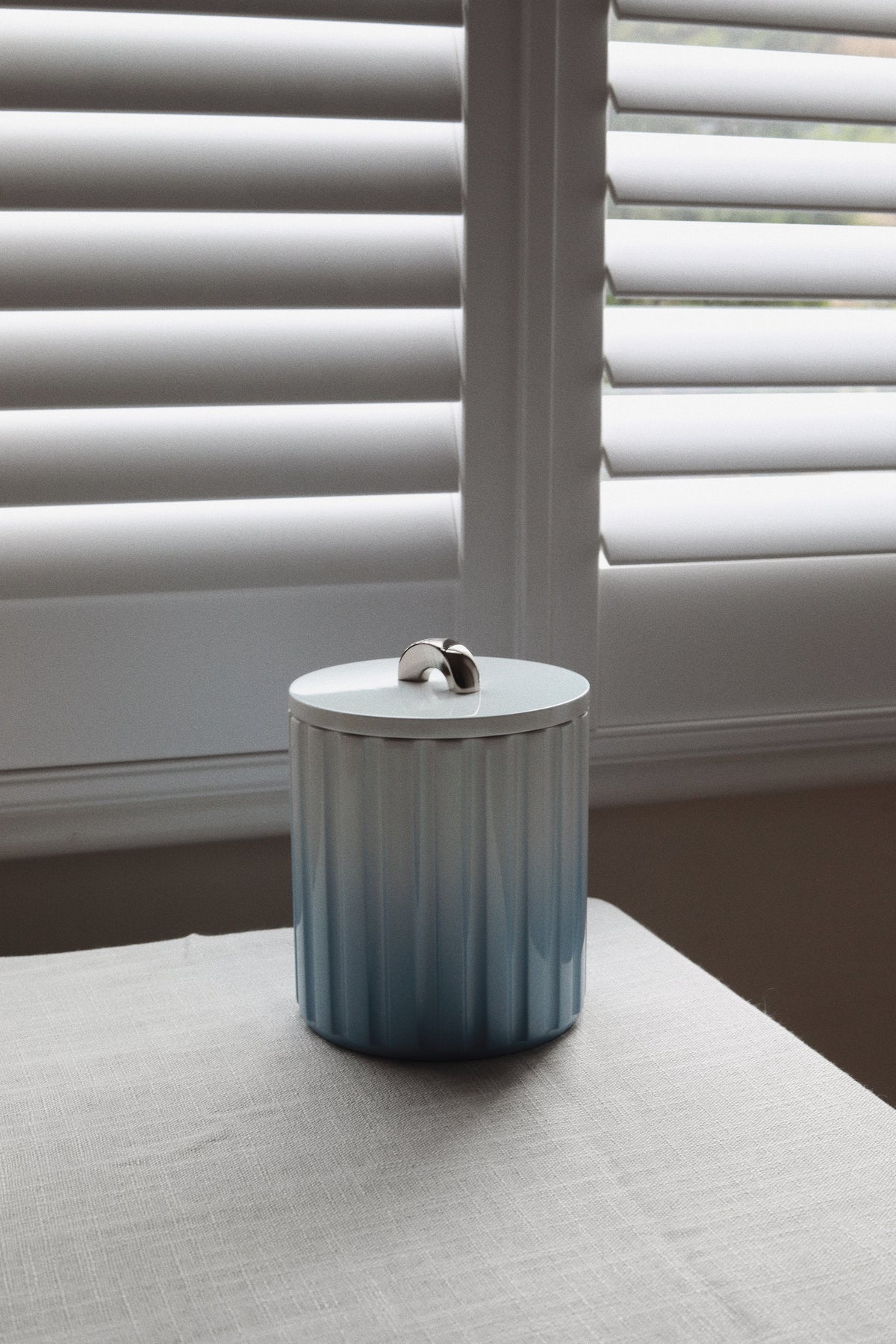 Vinidec fluted lacquer ice bucket with a soft ombré gradient from ice blue to deep slate, featuring a curved chrome lid handle.